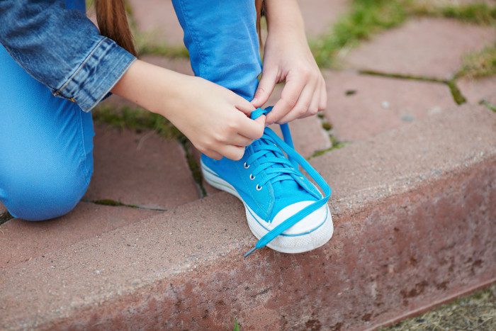 A person tying their shoe on the ground