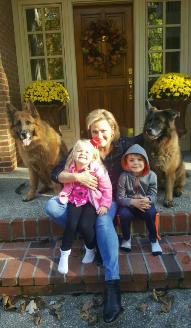A woman and two children sitting on the steps of a house.