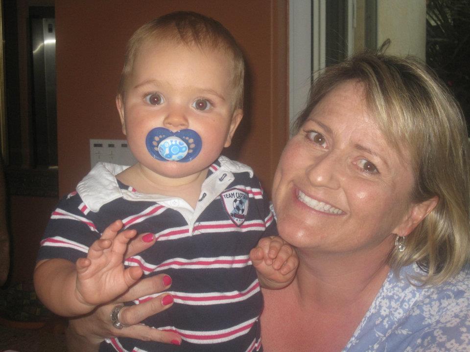 A woman holding a baby with a pacifier in her mouth.