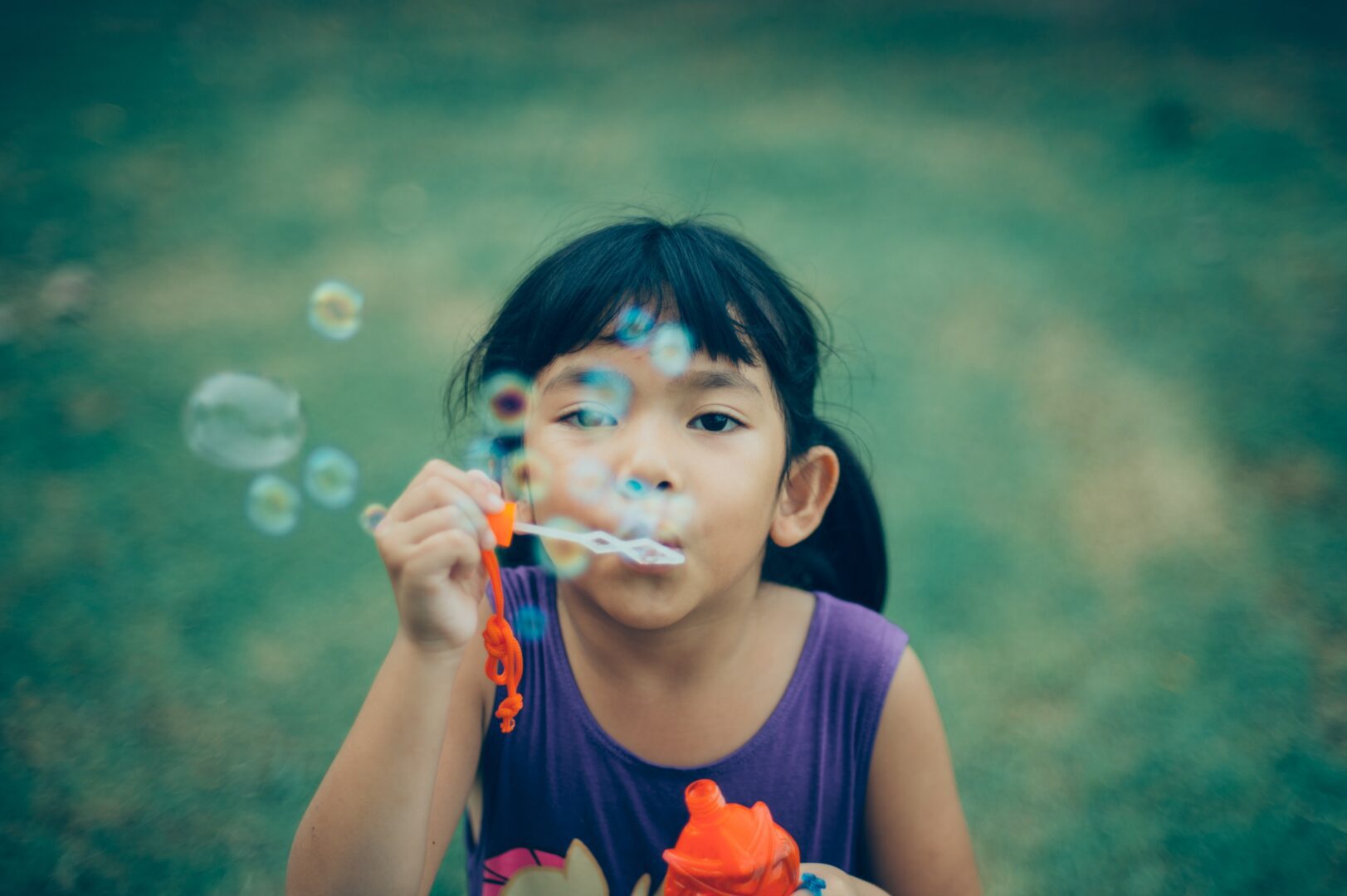 A little girl blowing bubbles with her toy.